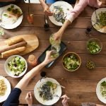 An overhead shot of a dining table featuring various pasta dishes and salads shared by a group.