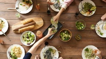 An overhead shot of a dining table featuring various pasta dishes and salads shared by a group.