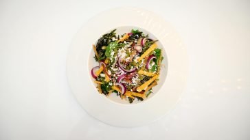 Top-down view of a colorful, nutritious vegetable salad with diverse toppings on a white plate.