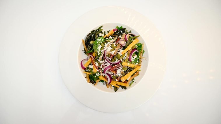 Top-down view of a colorful, nutritious vegetable salad with diverse toppings on a white plate.
