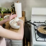 A woman in a kitchen cooking and preparing rice for a meal. Indoor setting with focus on food preparation.