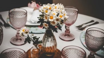 Charming table setup with vintage glasses and daisy flower arrangement, perfect for elegant dining occasions.