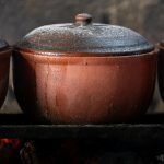 Close-up of Vietnamese clay pots cooking over an open fire, showcasing traditional culinary methods.
