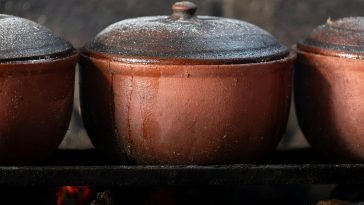 Close-up of Vietnamese clay pots cooking over an open fire, showcasing traditional culinary methods.