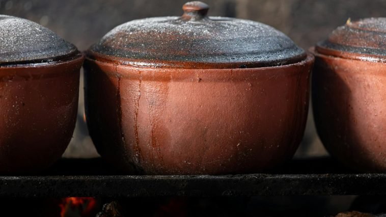 Close-up of Vietnamese clay pots cooking over an open fire, showcasing traditional culinary methods.