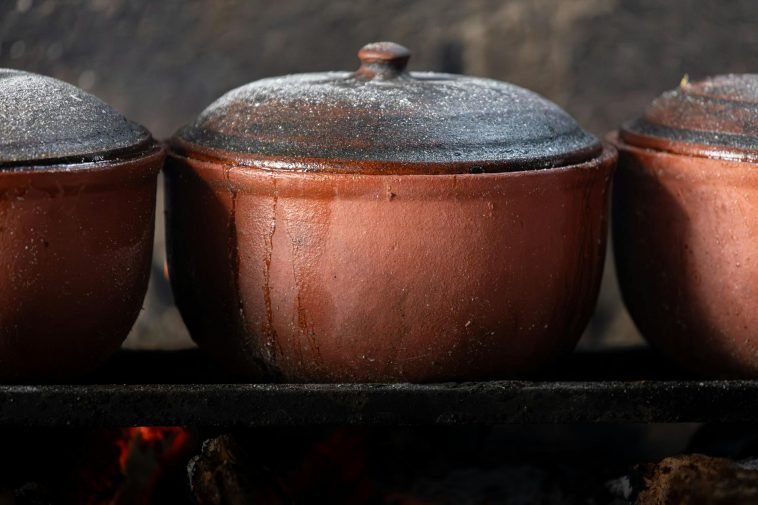 Close-up of Vietnamese clay pots cooking over an open fire, showcasing traditional culinary methods.