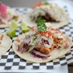 Close-up of colorful chicken tacos topped with fresh vegetables and cheese, perfect for Mexican cuisine lovers.