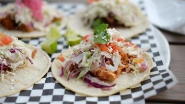Close-up of colorful chicken tacos topped with fresh vegetables and cheese, perfect for Mexican cuisine lovers.