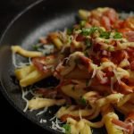 Delicious close-up of loaded French fries with melted cheese, bacon, and herbs.