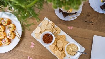 Top-down view of a table with assorted crackers, dips, and finger foods elegantly arranged.