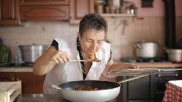 A woman savoring the aroma of a freshly cooked dish in a cozy kitchen setting.