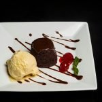 Indulge in rich chocolate lava cake with smooth ice cream and cherries.
