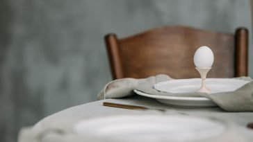 Elegant dining setup featuring a single egg in a minimalist table setting, perfect for spring themes.