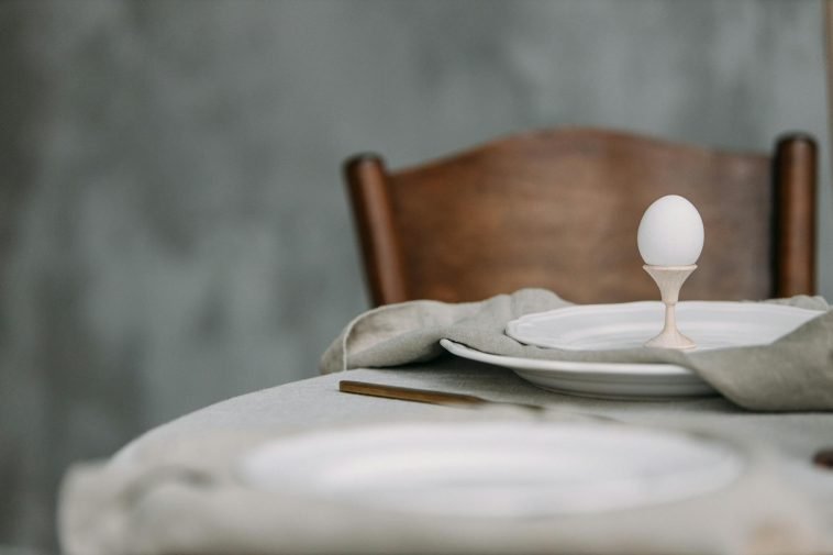 Elegant dining setup featuring a single egg in a minimalist table setting, perfect for spring themes.