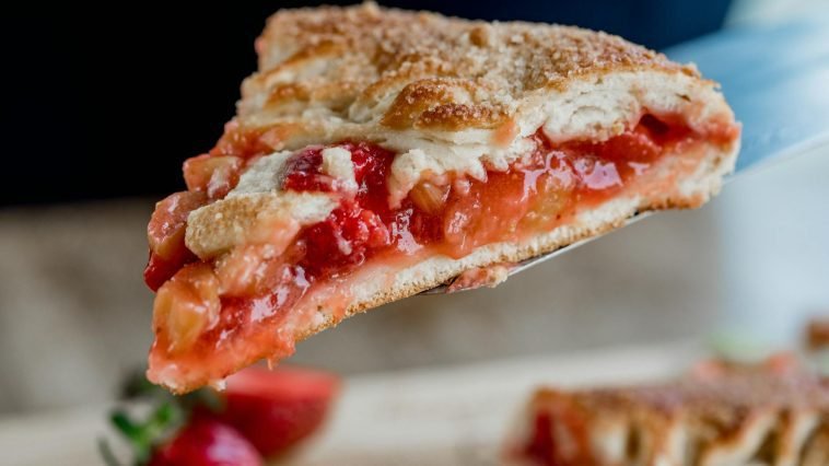 Delicious close-up of a freshly baked strawberry rhubarb pie slice on a spatula.