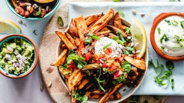 A vibrant platter of savory sweet potato fries with fresh toppings, perfect for a tasty snack.