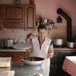 A woman cooking at home, showcasing culinary skills in a rustic kitchen setting.