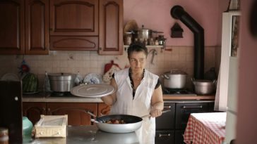 A woman cooking at home, showcasing culinary skills in a rustic kitchen setting.
