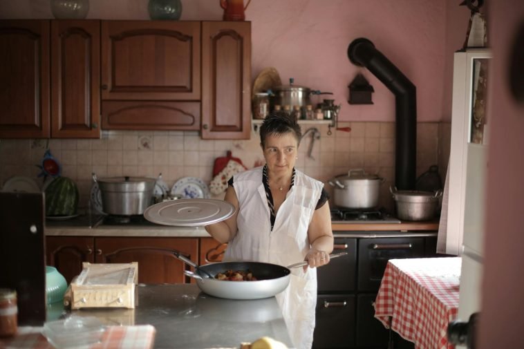 A woman cooking at home, showcasing culinary skills in a rustic kitchen setting.