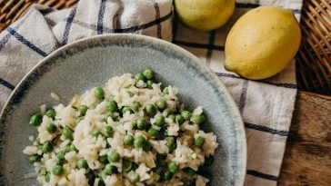 Close-up of a tasty pea risotto served with ripe lemons, highlighting the rich Italian flavors.