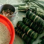 Banh Tet preparation with banana leaves, rice, and pork for Lunar New Year celebration.