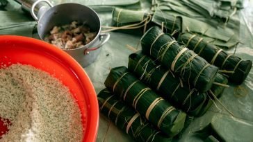 Banh Tet preparation with banana leaves, rice, and pork for Lunar New Year celebration.