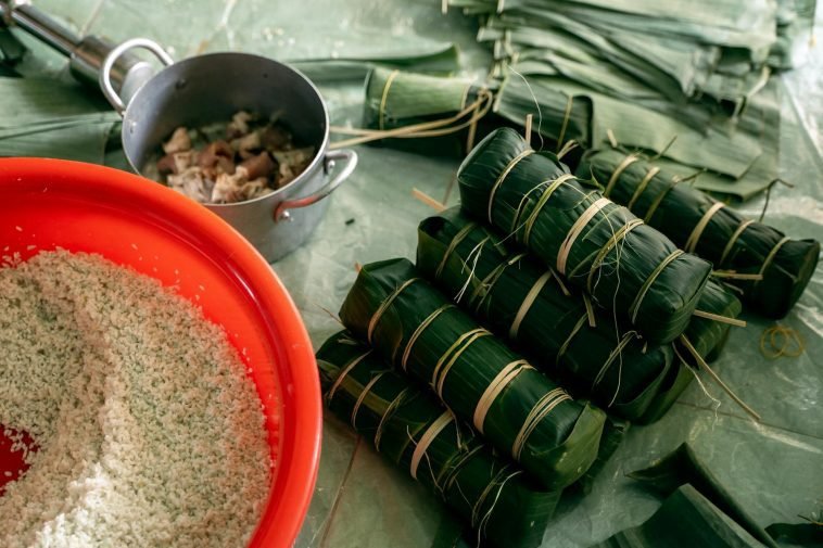 Banh Tet preparation with banana leaves, rice, and pork for Lunar New Year celebration.
