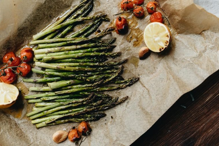 Delicious grilled asparagus with roasted cherry tomatoes and lemon, perfect for a healthy meal.