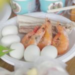 A vibrant dish featuring shrimps, eggs, and pork belly on a plate.