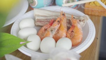 A vibrant dish featuring shrimps, eggs, and pork belly on a plate.