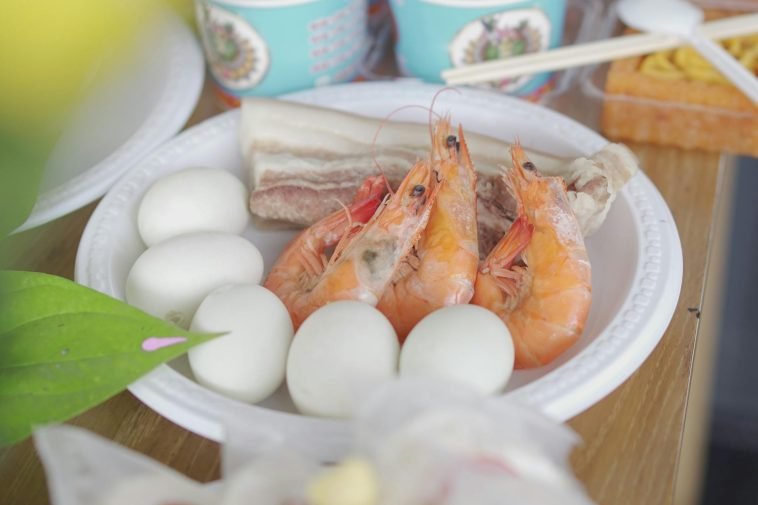 A vibrant dish featuring shrimps, eggs, and pork belly on a plate.