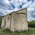 Historic Romanesque church in Huesca, Aragón, with a dramatic cloudy sky background.