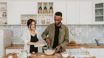 A couple collaboratively prepares a meal in a stylish contemporary kitchen setting.