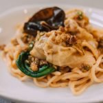 A delicious Asian noodle dish topped with dumplings and garnished on a plate.