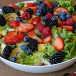 A vibrant bowl of fresh fruit and greens showcasing strawberries, kiwis, and berries, perfect for healthy eating.