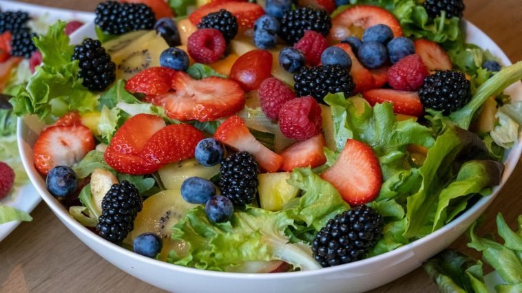 A vibrant bowl of fresh fruit and greens showcasing strawberries, kiwis, and berries, perfect for healthy eating.