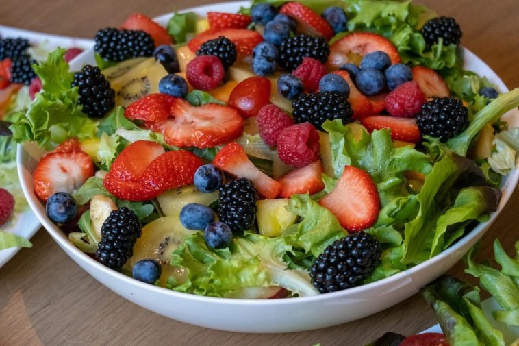 A vibrant bowl of fresh fruit and greens showcasing strawberries, kiwis, and berries, perfect for healthy eating.