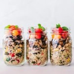 Three jars of colorful quinoa salad with mushrooms and tomatoes, perfect for a healthy meal.