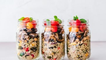 Three jars of colorful quinoa salad with mushrooms and tomatoes, perfect for a healthy meal.