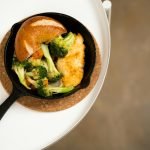 Close-up of a chicken skillet with broccoli, carrots, and bread, perfect for a healthy meal.
