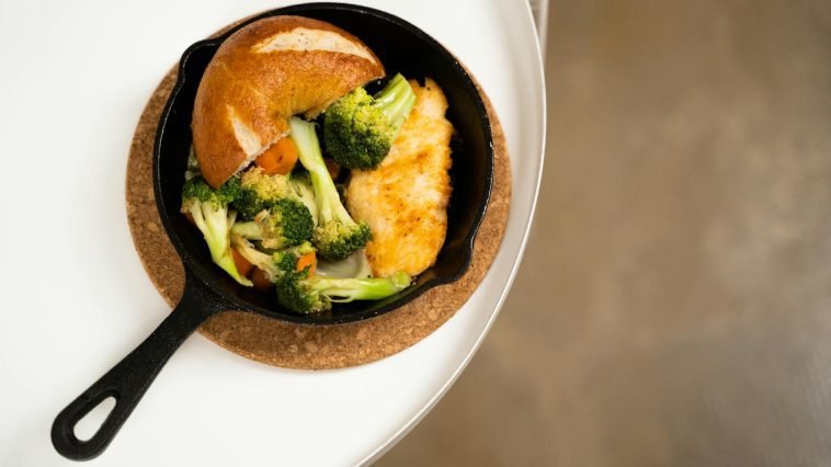 Close-up of a chicken skillet with broccoli, carrots, and bread, perfect for a healthy meal.