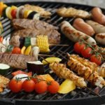 A vibrant assortment of grilled meats, sausages, and vegetables on a barbecue grill.