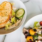 Fresh toasted sandwich with lettuce, cucumber, and a vibrant chicken salad on the side.