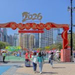 Crowds enjoying the vibrant 2026 Lunar New Year Fair at Victoria Park, Hong Kong under clear blue skies.