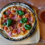 Delicious homemade pizza topped with salami, cherry tomatoes, and basil leaves, freshly baked.