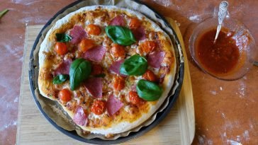 Delicious homemade pizza topped with salami, cherry tomatoes, and basil leaves, freshly baked.