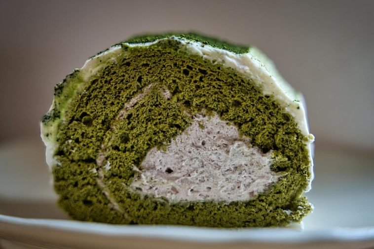 Delicious matcha Swiss roll cake with creamy filling in a close-up view.