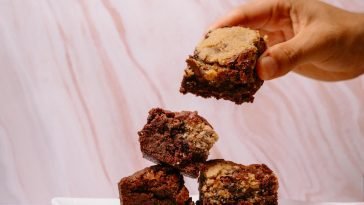 A stack of delicious homemade brownies being picked up by hand, perfect for dessert lovers.