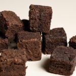 Close-up of rich chocolate brownie cubes on a neutral background, perfect for dessert lovers.