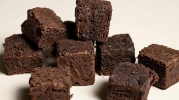 Close-up of rich chocolate brownie cubes on a neutral background, perfect for dessert lovers.